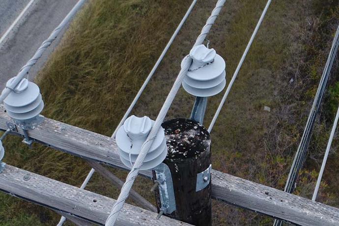 Aerial drone image of utility pole and active cables.